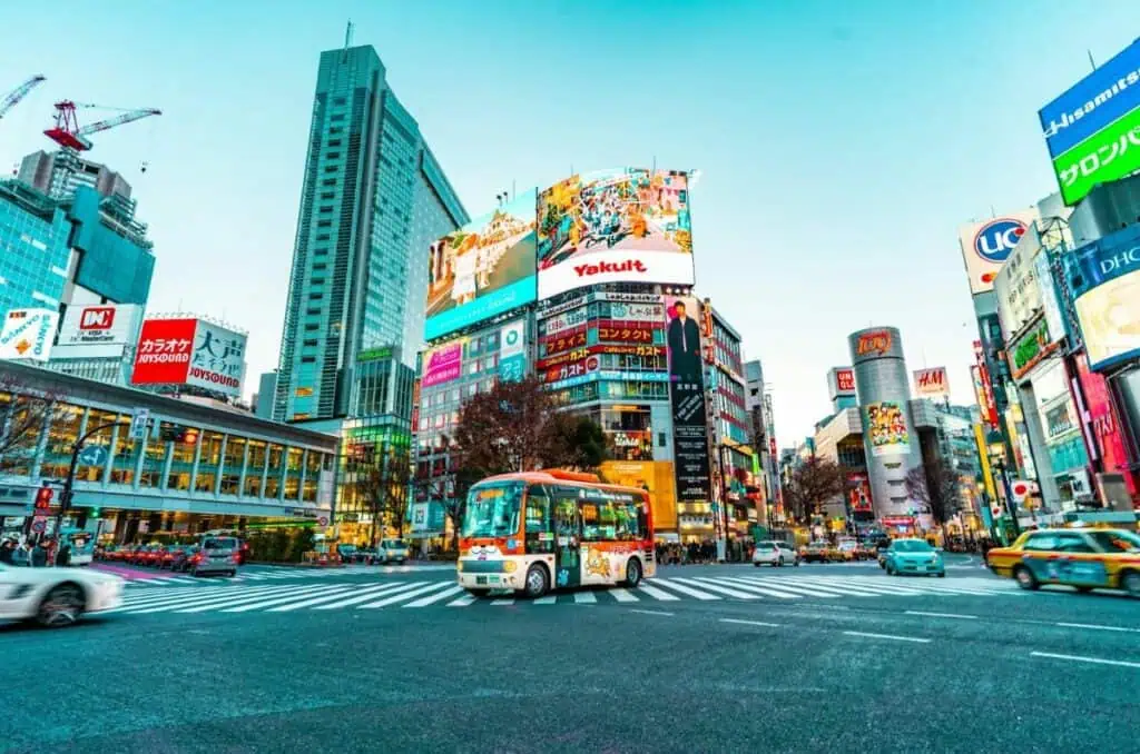 Vibrant street scene in Tokyo's Shibuya district with neon signs, billboards, and traffic